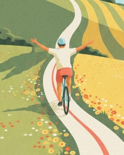 Le cycliste de dos, bras ouverts, sur une route sinueuse bordée de fleurs