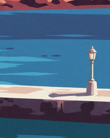 A pale street lamp and its shadow on the quay beside the blue water of Ammoudi harbour