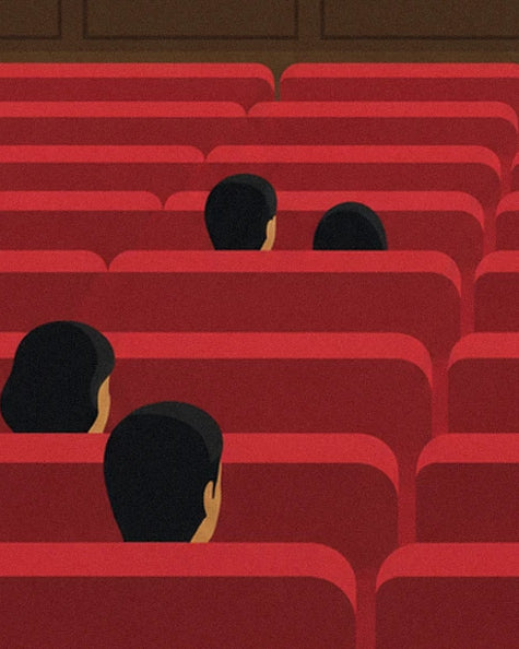 The audience seen from behind among the rows of red seats in the hall