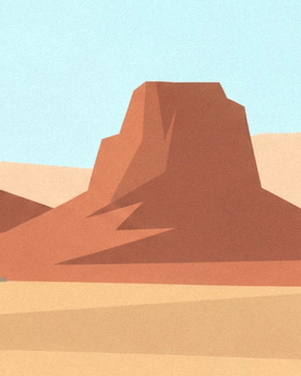 A red rock butte with sharp edges, rising from the sand beneath a pale blue sky